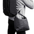 A cooler bag in a grid pattern, featuring a shoulder strap, being carried on the side of a person with a backpack.