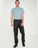 Lightweight black nylon waterproof rain pants displayed on a male model wearing a blue t-shirt. Features an elastic waistband.