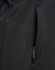 A close-up of a black softshell jacket featuring a zipped pocket. The fabric appears smooth and durable.