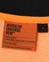 A close-up of an orange and black polo shirt with a label detailing standards and sizing. It has a logo.
