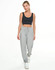 A woman in a black crop top and grey sweatpants stands against a white background. The sweatpants feature a drawstring waist.