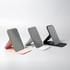 Three pocket mirrors in pink, grey, and black, each with a sleek, modern design and a stand.