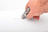 A correction tape dispenser in grey, being used to cover handwritten text on white paper.