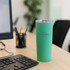 A drink bottle in mint green, with a stainless steel body and lid, sits next to a keyboard on a desk.