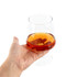 A brandy snifter filled with amber liquid, held in a hand, featuring a clear glass design.