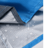 A close-up of a blue polyester picnic blanket featuring a water-resistant underside with droplets. It has a logo.