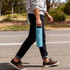 A drink bottle in pastel blue with a handle, held by a person walking outdoors along a roadside.