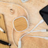 A bamboo and white USB charger cable with multiple connectors rests on a wooden surface beside a phone and stationery.