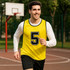 A yellow training bib with a black number '5', worn over a white long-sleeve shirt, on a basketball court.