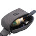 A grey anti-theft sling bag with a drink bottle, sunglasses, and a wallet visible inside.