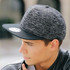 A black and grey cap with a textured design and a flat brim, featuring a logo on the front.