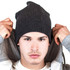 A grey ribbed beanie worn by a model with a neutral expression, holding up the hood of a jacket.