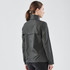 A women's rain jacket in dark grey, featuring a high collar and a flap at the back, with a logo present.