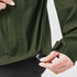 A green Women's Vertex Stormshell jacket with a person adjusting the bottom hem, featuring a logo.