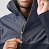 A man in a navy rain jacket with a zipped collar and a logo, showcasing the fabric and design details.
