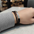 A double-layer leather bracelet featuring black and silver elements, displayed on a wrist against a neutral background.