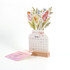 A desk calendar featuring a floral design with pink and yellow flowers, set in a wooden holder.