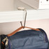 A round, silver desk hook holding a navy backpack, attached to a white shelf above.