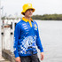 A man wearing a blue long sleeve fishing polo with a yellow collar and a matching bucket hat, beside a waterway.