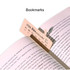 A pink bookmark positioned in a book, with a calendar date visible and a subtle logo in the corner.