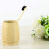 A natural bamboo toothbrush stands upright in a bamboo holder, with a backdrop of white and green flowers.