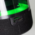 A close-up of a black Bluetooth speaker with a green light, featuring AUX and USB ports on the side.