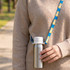 A drink bottle with a silver metallic finish and a blue lanyard featuring a pattern of cute animals.