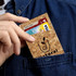 A cork card wallet in a pocket, holding a debit card and a credit card. The wallet features a logo design.