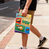 A person holds a multicoloured tote bag featuring various playful graphic designs and a logo.