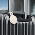 A sleek silver tracking tag attached to a black suitcase handle, featuring a simple logo.