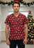 A unisex Christmas scrub top in red featuring festive patterns, standing in front of a decorated Christmas tree.