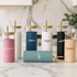A drink bottle collection featuring various styles in pastel and neutral colours, each with a bamboo lid and a straw.