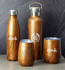 A drink bottle and tumblers in a wood finish, featuring logos, set against a grey background.