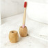 A bamboo toothbrush stand in natural wood tones, featuring two holders with a toothbrush placed in one.