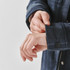 A plaid jacket in a dark blue hue, featuring a Sherpa lining and buttoned cuffs, is being showcased with hands adjusting the sleeve.