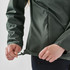A green women's full zip rain jacket with a drawstring at the hem being adjusted by a person.