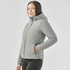 A woman wearing a grey thermal puffer jacket with a hood, featuring side pockets and a fitted design.