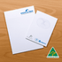 A4 notepad with lined pages, featuring a logo and an Australian Made badge, set on a wooden surface.