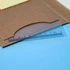 A clear plastic ruler with measurements rests on a brown notepad cover, featuring a simple design.