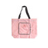 A pink foldable tote bag with black handles and a front zippered pocket. It features a logo on the front.