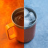 A stainless steel cup with a handle, featuring a vibrant orange and grey design, filled with hot liquid and ice.