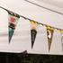 A set of colourful felt pennants with various outdoor designs, displayed on a string under a canopy.