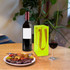 A clear jelly wine ice bag in vibrant yellow beside a bottle of red wine and a glass of red wine on a wooden table.