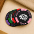 A set of black poker chips with colourful accents in green, purple, pink, and a lion logo in the centre.