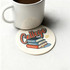A drink mug rests on a round, cream-coloured coaster featuring a design with books and the word "College".