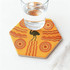 A hexagonal ceramic coaster in orange and yellow with a decorative pattern and a glass of water on top.