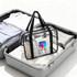 A clear tote handbag with black handles, containing toiletries and clothing items, placed inside a suitcase.