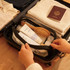 A waterproof transparent cosmetic bag in black, holding beauty products, a hairbrush, and travel essentials.