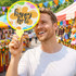 A colourful round fan featuring a festive design and the phrase "happy holi," held by a smiling man at a vibrant market.