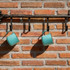 A drink bottle with an insulated design, featuring a light turquoise colour and a hanging loop, displayed on a brick wall.